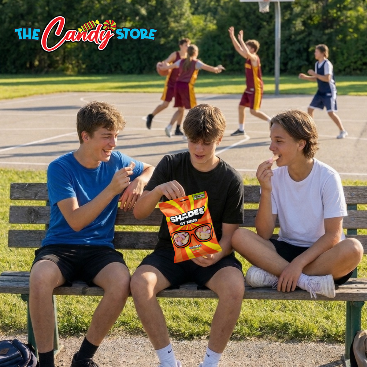 Three young men sitting on a wooden bench at a park, with one holding a bag of shades by Niko tropical blast. In the background, 4 basketball players are playing.
